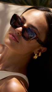 Woman wearing ANEA HILL 1946 sunglasses in Palm (green), a small, trendy frame for women. Consider ANEA HILL for Best Women Sunglass Brands.