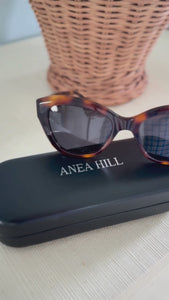 1946 sunglasses on a countertop, showcasing their small frame design perfect for women with smaller faces. The sleek, elegant silhouette highlights the timeless style and exceptional craftsmanship, ideal for those seeking a comfortable, flattering fit.