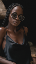 Load image into Gallery viewer, Model wearing high-end designer green tortoise sunglasses with gold bar.

