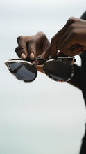 Load image into Gallery viewer, Model holding a dark green tortoise color acetate with elegant gold bar.
