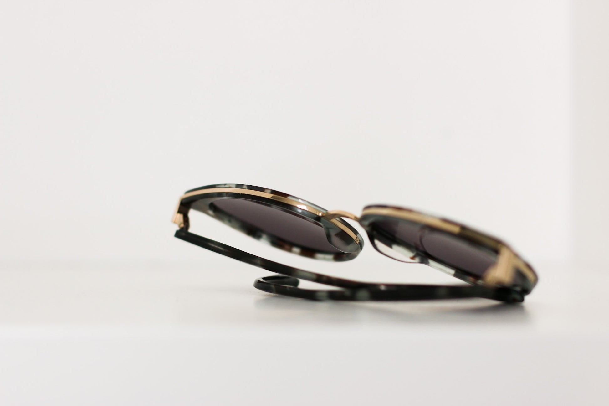 Limited Edition Nottingham Sunglasses with dark green tortoise color acetate and adjustable ear arms, showcasing the high-end designer detailing the gold bar across top of frame..