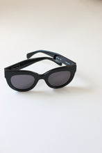 Load image into Gallery viewer, Exclusive black luxury sunglasses by ANEA HILL with adjustable acetate ear arms, part of the Around the World Collection.
