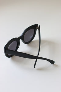 Back view of luxury oversized sunglasses with silver-tone hinges and matte black acetate frames.